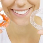 A girl holds braces for teeth straightening in her hands.